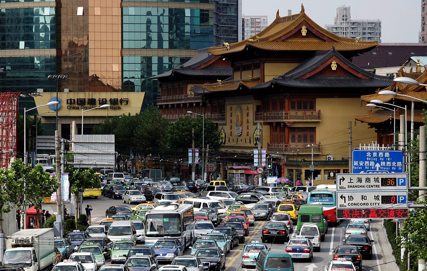 Traffic at a busy intersection in front of a buddhist temple in the centre of Shanghai, China.